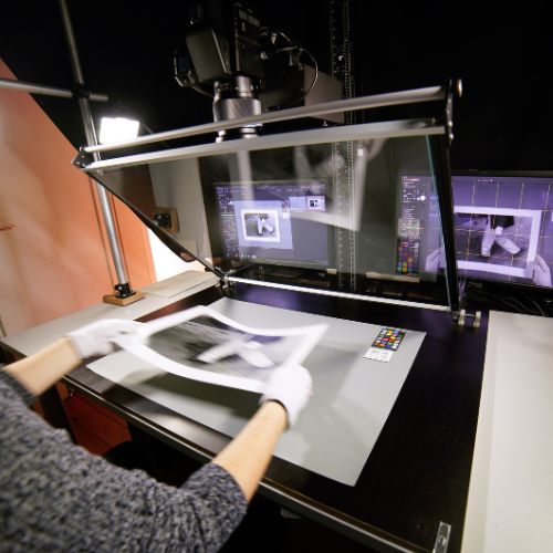 Eine geschulte Mitarbeiterin legt einen großen Fotoabzug in die Reprostation.